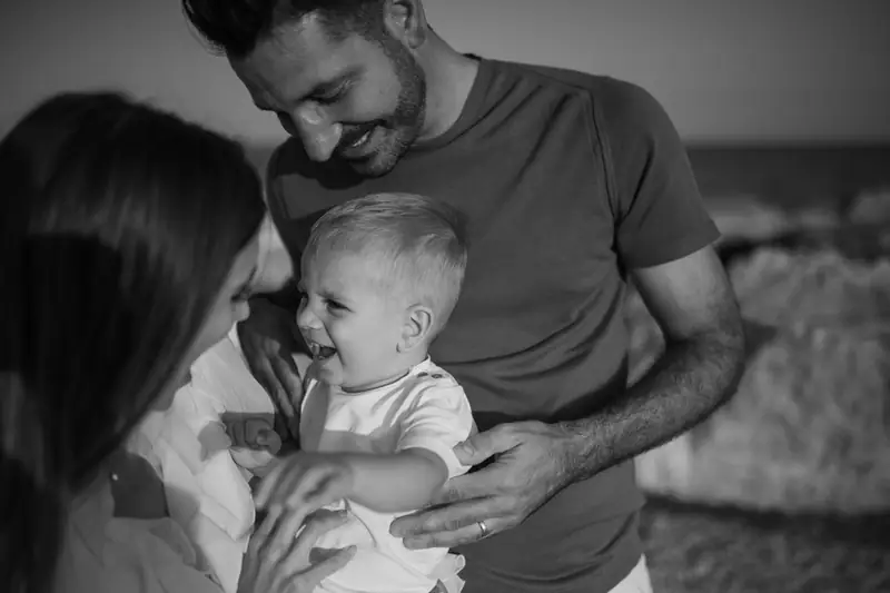 In bianco e nero, un uomo sorride a un bambino piccolo che ride