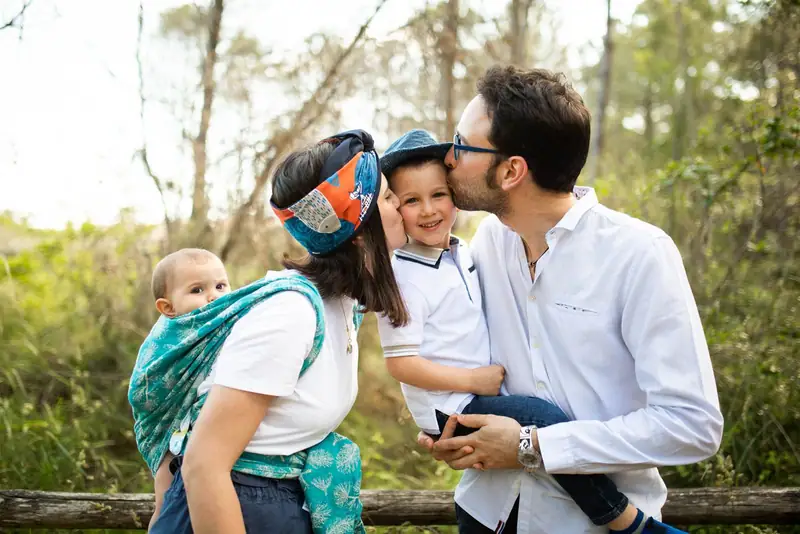 Paolo e Caterina con i loro bambini nel bosco, il più piccolo nella fascia