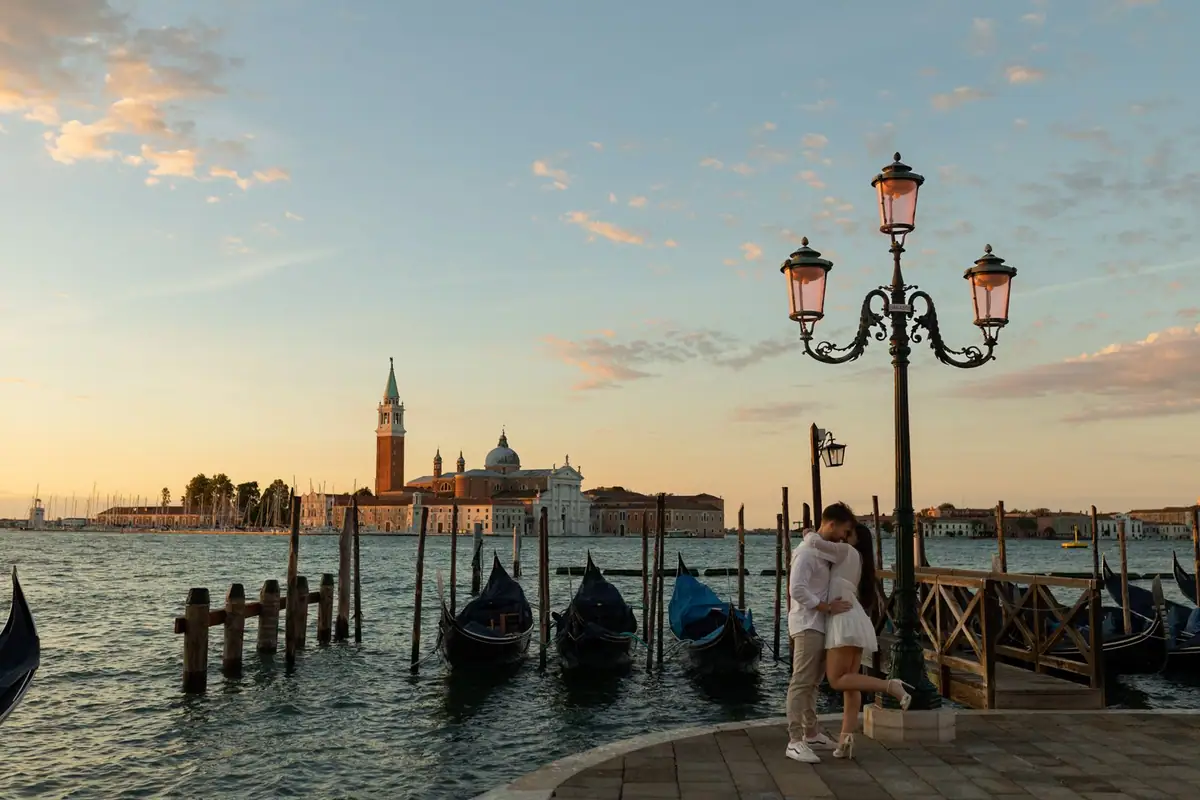 Sam e Angelica abbracciati sulla riva, le gondole e San Giorgio Maggiore all’alba