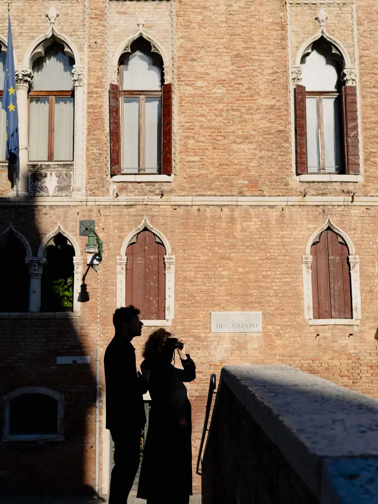 Due allievi in controluce fotografano una facciata gotica a Venezia