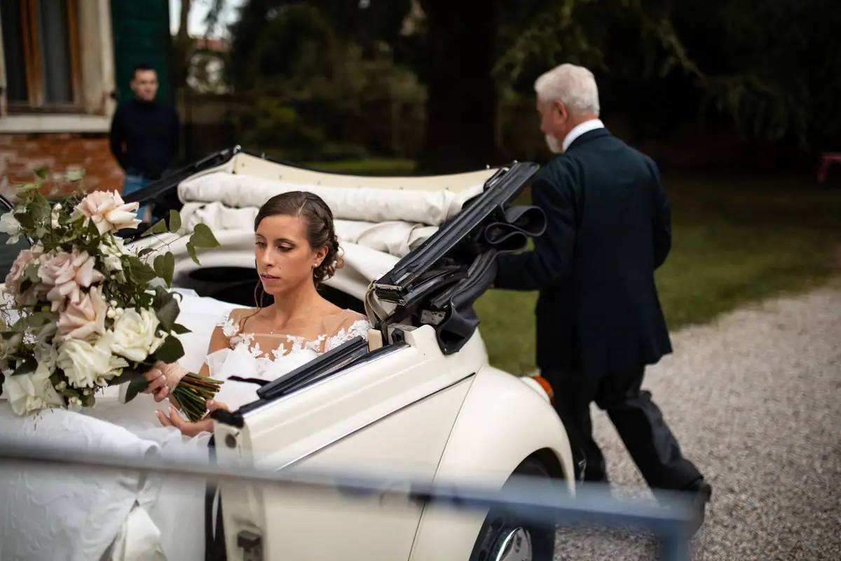 La sposa arriva su un maggiolino bianco decappottabile, chi l’accompagna le apre la portiera